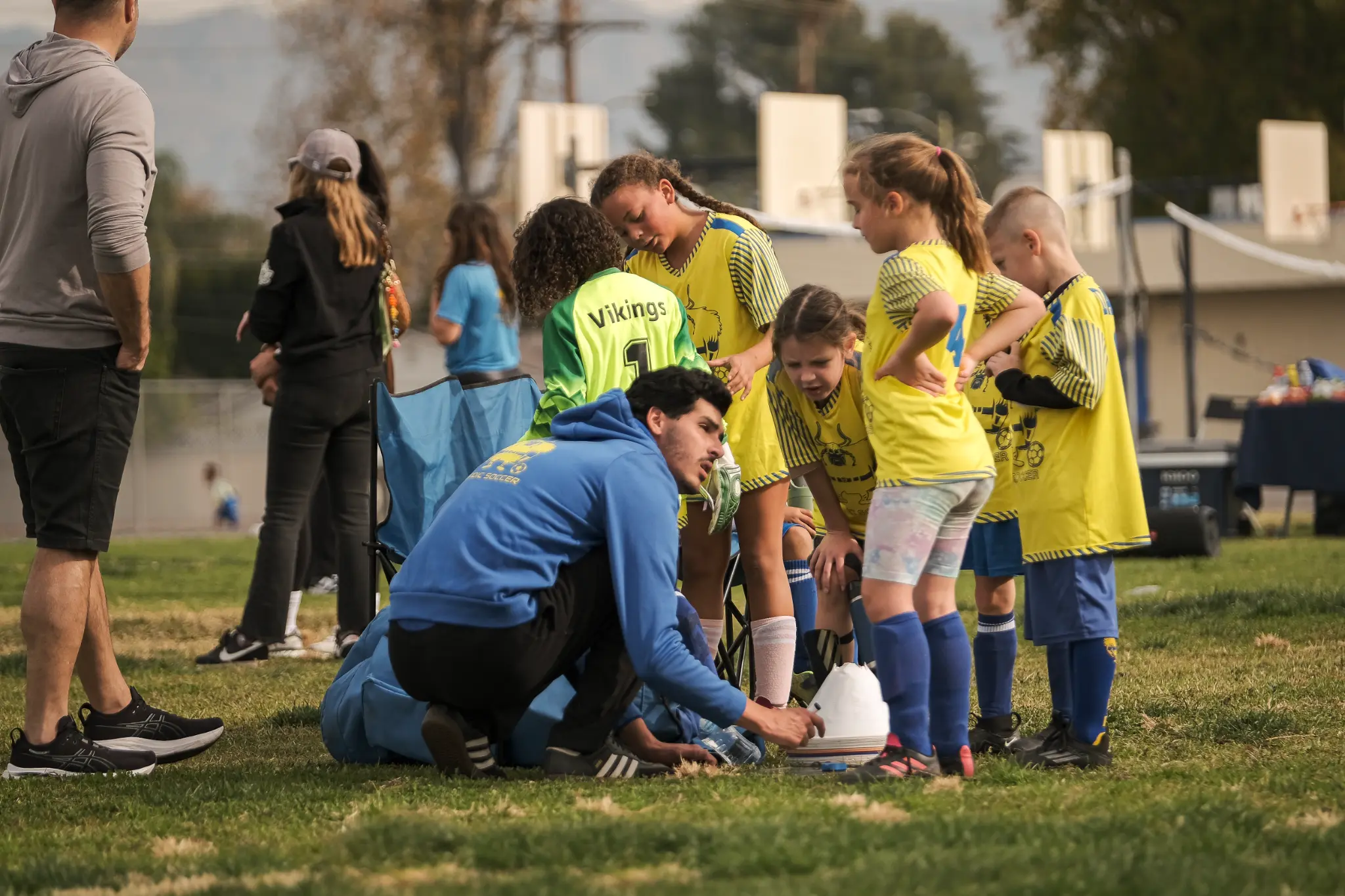 Nordic Soccer youth players in blue and yellow jerseys during team huddle with coach at Los Angeles soccer field